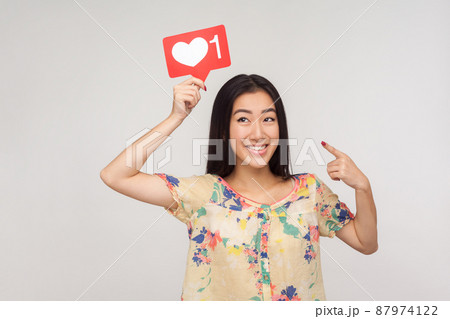 Choose trendy social media content, Happy enthusiastic asian girl in blouse pointing at heart icon over her head, recommending to subscribe and follow interesting blog. indoor studio shot, isolated 87974122