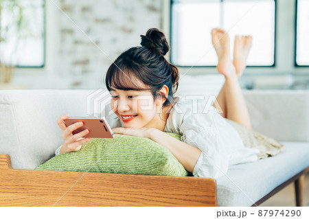 リビングでスマホを見る若い女性 87974290