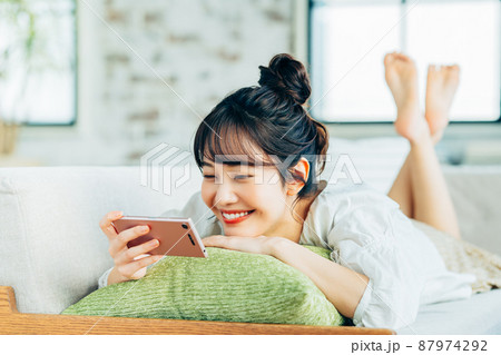 リビングでスマホを見る若い女性 リビングでスマホを見る若い女性 87974292