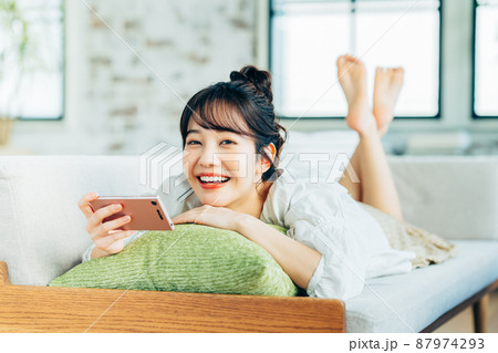 リビングでスマホを見る若い女性 87974293