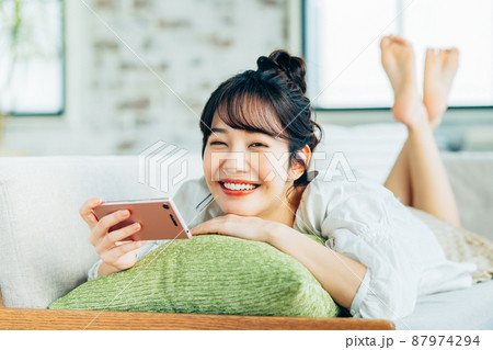 リビングでスマホを見る若い女性 87974294