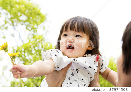 新緑の樹木を背景に幼い娘を持ち上げる父のクローズアップ。幸せ,愛情,育児イメージ 新緑の樹木を背景に幼い娘を持ち上げる父のクローズアップ。幸せ,愛情,育児イメージ 87974508