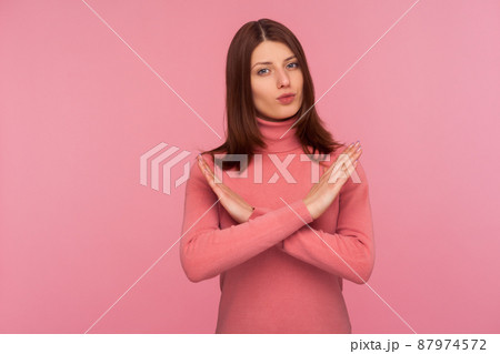 Strict bossy woman with brown hair in pink sweater showing x sign with hands, there is no way more, hopelessness. Indoor studio shot isolated on pink background Strict bossy woman with brown hair in pink sweater showing x sign with hands, there is no way more, hopelessness. Indoor studio shot isolated on pink background 87974572