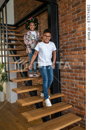 Boy and girl walking down stairs smiling at camera Boy and girl walking down stairs smiling at camera 87974802
