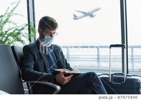 airport passenger in a protective mask taking notes in his noteb 87975940