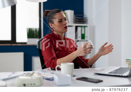 Employee sitting at startup desk encounters unexpected laptop error. Businesswoman in red shirt looking puzzled at notebook computer screen. Small business owner having a difficult day. Employee sitting at startup desk encounters unexpected laptop error. Businesswoman in red shirt looking puzzled at notebook computer screen. Small business owner having a difficult day. 87976237