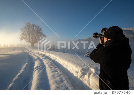 Hiker photographer taking pictures of snowy nature in winter mountains. Hiker photographer taking pictures of snowy nature in winter mountains. 87977540