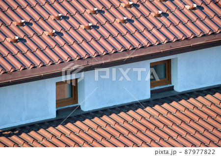 Closeup snow guard for safety in winter on house roof top covered with steel shingles. Tiled covering of building 87977822