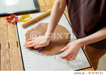Woman hands cooking homemade cookies from rolled dough with culinary molds on silicone baking mat 87978755