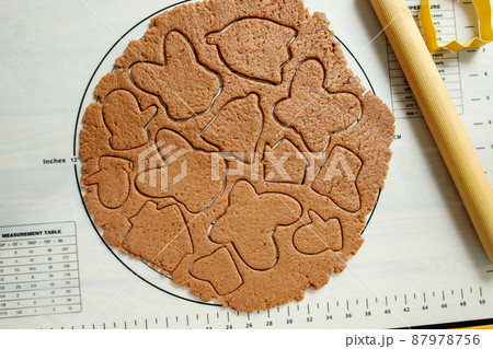Top view of rolled dough for homemade cookies with squeezed cookies of various shapes on a silicone baking mat Top view of rolled dough for homemade cookies with squeezed cookies of various shapes on a silicone baking mat 87978756