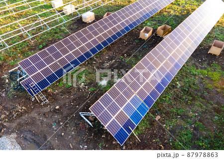 Aerial view of solar power plant under construction on green field. Assembling of electric panels for producing clean ecologic energy. 87978863