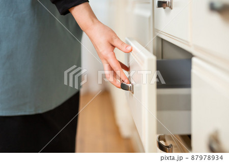 Close-up of a woman's hand closing a kitchen table drawer. Selective soft focus 87978934