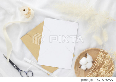 Blank greeting card invitation Mockup 5x7 on envelope with dry flowers and ribbon on white fabric background, flat lay, mockup Blank greeting card invitation Mockup 5x7 on envelope with dry flowers and ribbon on white fabric background, flat lay, mockup 87979255