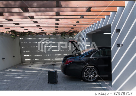 A photo of a suitcase standing next to a car in a luxury garage. Selective focus  87979717