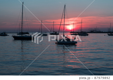 Sunrise on the seashore. In the silhouette of the ships in the harbor. Selective focus Sunrise on the seashore. In the silhouette of the ships in the harbor. Selective focus 87979892