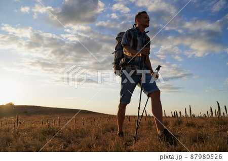 Hike mountain man hiking travel with backpack and trekking poles walking at adventure and sunset. High quality photo. 87980526