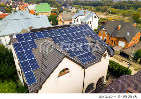 Aerial view of a private house with solar photovoltaic panels for producing clean electricity on roof. Autonomous home concept. Aerial view of a private house with solar photovoltaic panels for producing clean electricity on roof. Autonomous home concept. 87980836