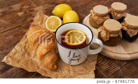 Lemon tea, home made jam, croissant on wooden table. Breakfast concept. Lemon tea, home made jam, croissant on wooden table. Breakfast concept. 87981770