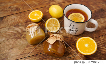 Sweet breakfast. Cup of black tea with lemon. Lemons and jars with jam 87981786