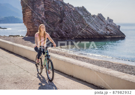 Woman tourist on a bicycle explores Budva in Montenegro. Cycling in Montenegro concept 87982932