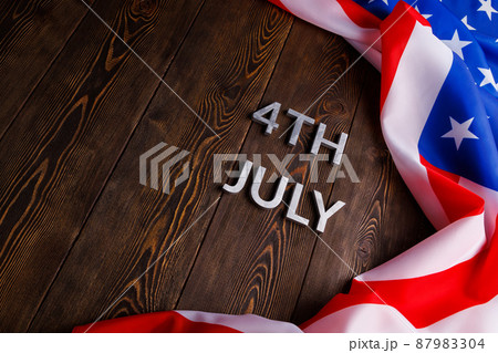 the words 4th july and crumpled usa flag on flat textured wooden surface background 87983304