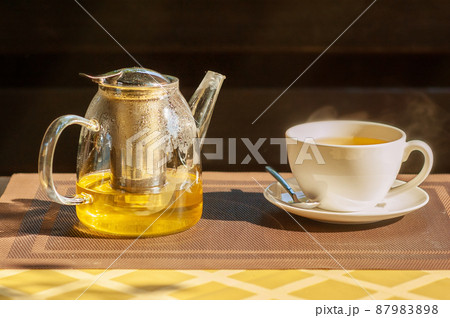 Green tea in a teapot on the table. Tea in a white cup. Green tea in a teapot on the table. Tea in a white cup. 87983898