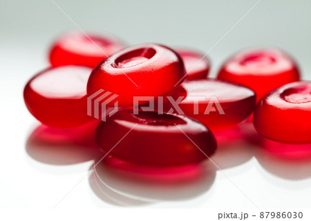 Pile of red pills isolated on white surface with reflection Pile of red pills isolated on white surface with reflection 87986030