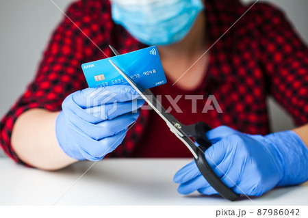 Caucasian female person cutting bank card with scissors 87986042