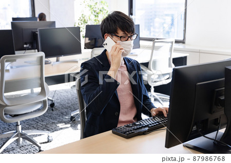 テレワーク中に出社を余儀なくされまばらに座る会社員 87986768