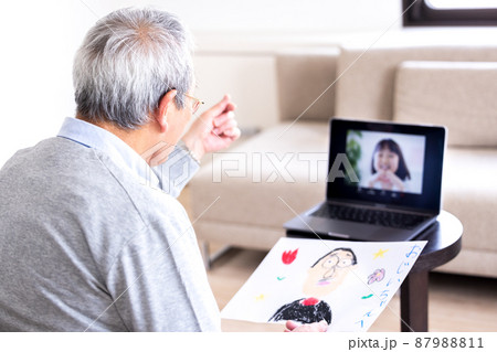 ビデオ通話　オンラインで繋がった孫に指ハートを送るシニア男性 87988811