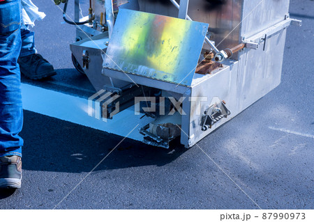 Worker thermoplastic spray marking machine painting work on the street 87990973