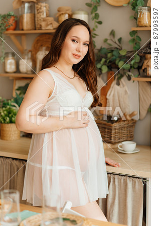a pregnant woman in white peignoir. beautiful and sexy clothes for pregnant.  87993597