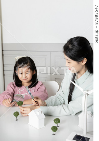 Asian Korean mom and daughter observing solar and wind power models Asian Korean mom and daughter observing solar and wind power models 87995547