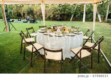 Wedding. Banquet. The chairs and round table for guests, served with cutlery. 87996015