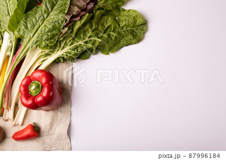 Overhead view of fresh chard with red bell and chili peppers by copy space on white background 87996184