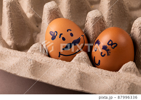 Close-up of creative drawing on brown eggs in carton 87996336