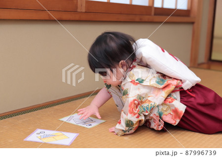 1歳の誕生日に袴を着て一升餅を背負って選び取りをする子供 87996739