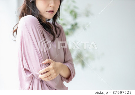 部屋着のまま体を抱え込む体調不良の女性 87997525