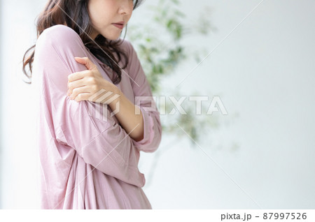 部屋着のまま体を抱え込む体調不良の女性 87997526