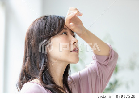 部屋着のまま額に手を当てる体調不良の女性 87997529