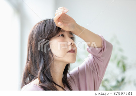 部屋着のまま額に手を当てる体調不良の女性 87997531