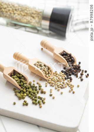 Three different types of pepper spice. Green, white and black peppercorn in wooden scoops. 87998206