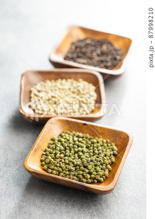 Three different types of pepper spice. Green, white and black peppercorn in bowls. Three different types of pepper spice. Green, white and black peppercorn in bowls. 87998210