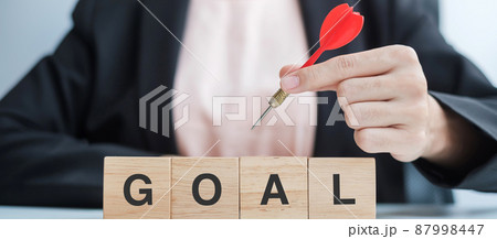 Hand holding red dart over Goal block. target, aim, objective, leadership, Business and marketing concept Hand holding red dart over Goal block. target, aim, objective, leadership, Business and marketing concept 87998447