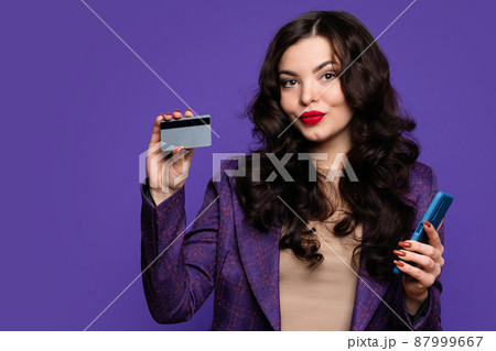 Woman holds credit card and smartphone 87999667