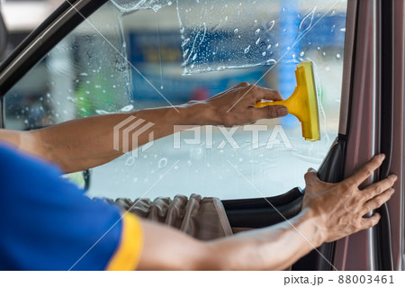 Technician Installing car window tint. Car window tinting series. Technician Installing car window tint. Car window tinting series. 88003461