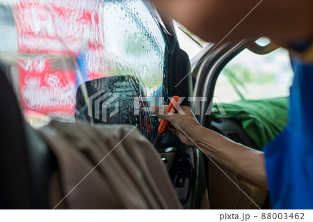 Technician Installing car window tint. Car window tinting series. Technician Installing car window tint. Car window tinting series. 88003462