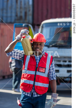 African American Container Warehouse Worker. Foreman carrying oil gallons. 88006097