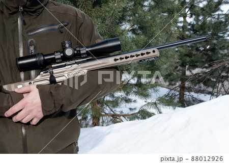 A sniper rifle with an optical sight in man`s hands winter day A sniper rifle with an optical sight in man`s hands winter day 88012926