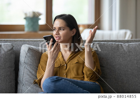 Young woman holding smart phone speaking on speakerphone Young woman holding smart phone speaking on speakerphone 88014855